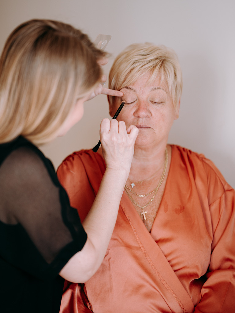 Mother of the bride with eyes closed while makeup is applied by Katarina Kate Ramic on wedding day in Hvar.