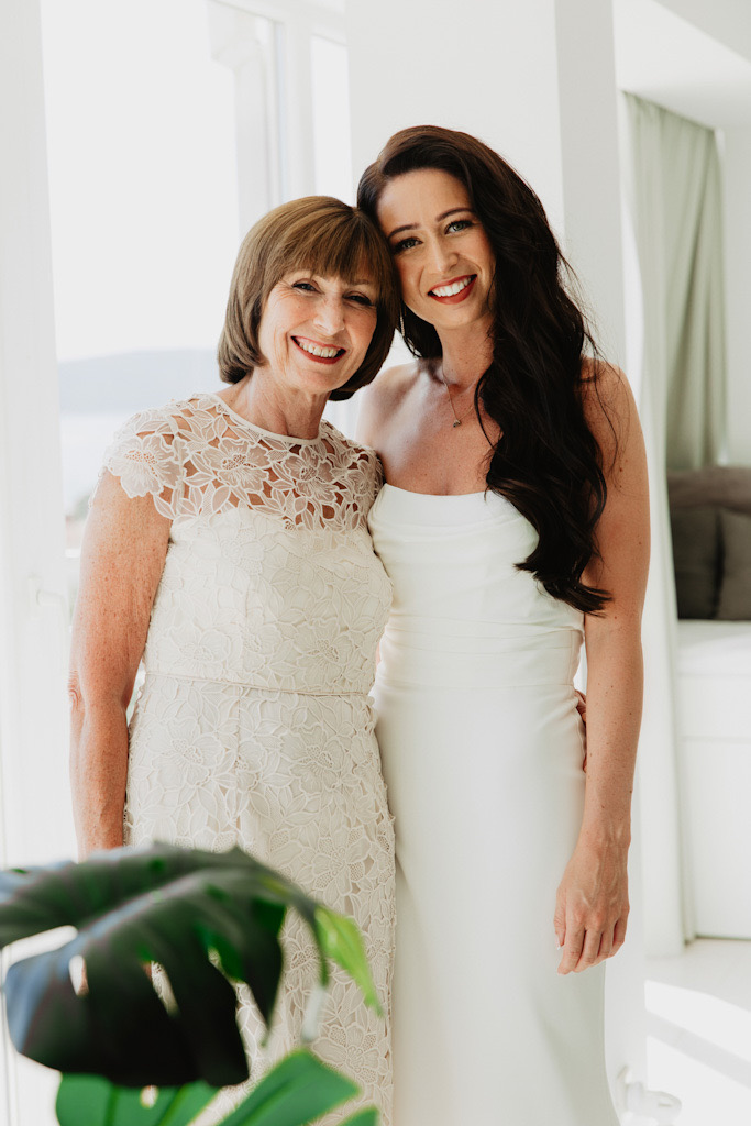 Bride in wedding dress and her mother smiling with heads leaning together on wedding day in Split, Croatia.